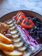 Healthy Porridge breakfast with greek yoghurt, mixed berries, strawberries, blackberries, pumpkin seeds, banana, chai seeds, peanut butter, almond nuts and peach slices. 
