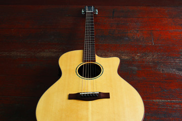The beautiful light brown guitar on a wooden floor