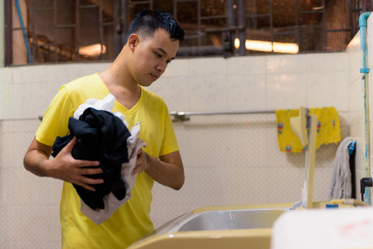 Portrait Of Young Asian Man Doing Laundry At Home