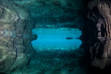 Light seeps into a dark, underwater cavern in the tropical Pacific Ocean. Caves and caverns riddle coral reefs and limestone islands.