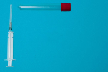 Flatlay, syringe and test tube on a blue background with place for text.