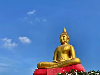 The big golden buddha with red base and the blue sky with cloud