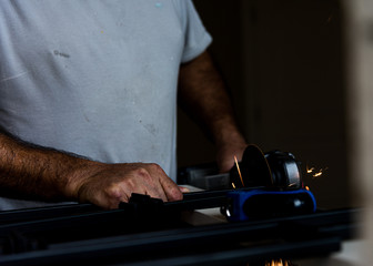 Man's hands working on sawing metal with sparks, POV