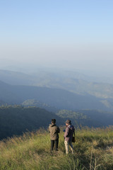 Fototapeta na wymiar Two man have on jacket stand on hilltop look at beautiful mountain view