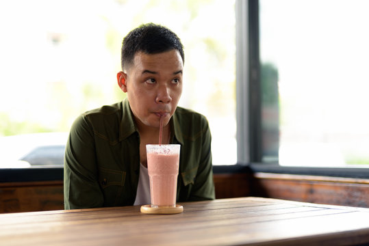 Young Asian Man Drinking Shake At The Coffee Shop