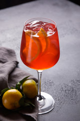 Alcoholic red cocktail aperol syringe with ice, orange slices in a wineglass with tangerines on a dark background. Bar menu. Background image, copy space