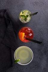 Alcoholic cocktails: Mojito, Daiquiri and aperol syringe on a dark background. Top view, flatlay. Bar menu. Background image, copy space