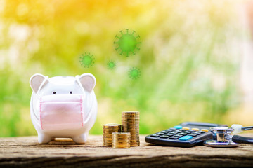 Sick piggy bank wearing surgical mask to prevent viruses and diseases put beside three stack gold...