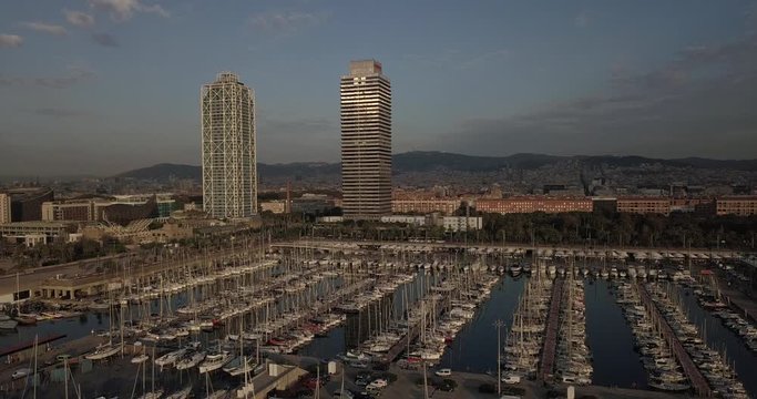 Aerial pedestal upwards boats at Port Olimpic and Mapfre tower background