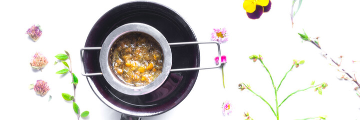 chamomile tea in clay cup, herbal flowers and leaf