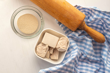 dried and fresh yeast on a white kitchen bacground with wooden rolling pin