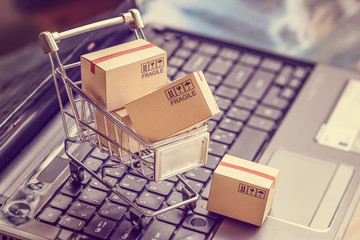 Boxes with shopping cart on a laptop computer keyboard - obrazy, fototapety, plakaty