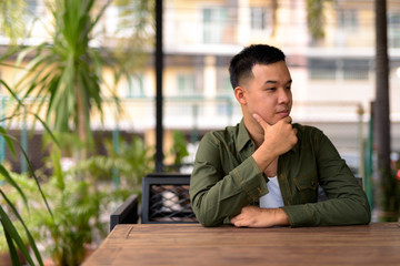 Young Asian man thinking at the coffee shop