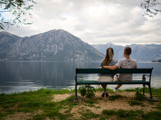 Naklejka na ściany i meble Couple sitting on a bench admiring еhe view of the Kotor Bay. Montenegro autumn 2019