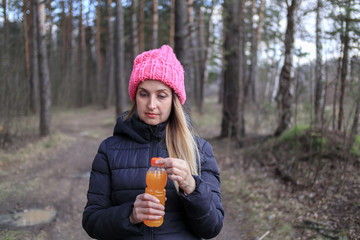Woman with bottle of orange juice or smoothie in the park