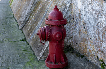 Fototapeta na wymiar Old red water hydrants on a street with old brick wall background. Vintage water hydrant found on an old street