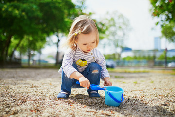 Adorable toddler girl playing with bucket and shovel