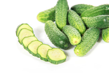 Group of fresh green pickling cucumbers with slices and on white background