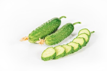 Fresh green pickling cucumbers with slices and on white background