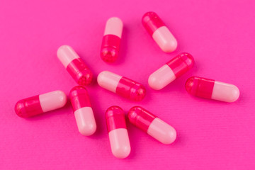 A lot of pink capsules, pills on a pink background.