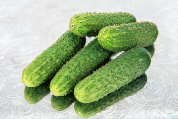 Fresh green pickling cucumbers on metal tray with folk ornament