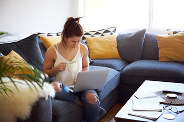 Woman working on laptop sat on sofa