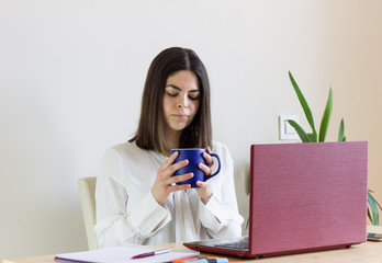 Happy casual woman teleworking from home due to Covid-19 situation. Drinking tea.