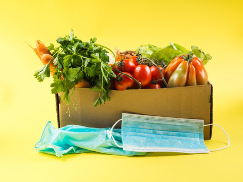 Fresh Produce, Food Staples Delivery Or Donation Box Concept On Yellow Background. Safe Shopping And Delivery During Coronavirus Pandemic With Face Masks And Disposable Gloves