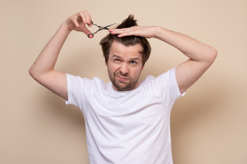 man trying to make a hairstyle by himself with scissors being on quarantine