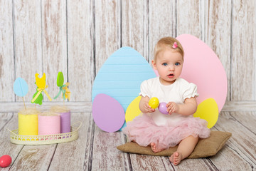 Cute girl with Easter eggs on the background of wooden wall. Girl play with eggs.
