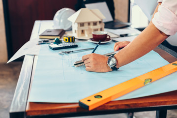 engineers holding a pen pointing to a building and  drawing outlay construction plan as guide for...
