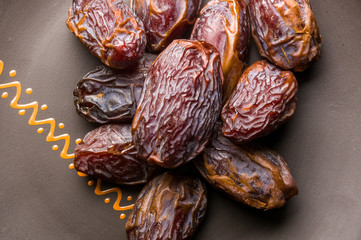 Big luxury dried date fruit in bowls on the dark surface, kurma ramadan kareem concept, close up.