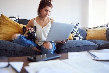 Young female working on sofa with pet dog