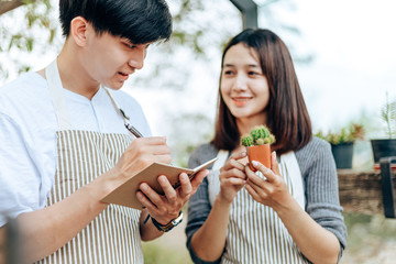 Women hold cactus and a man writing note in a book. Love couple enjoy hobby with darden cactus.