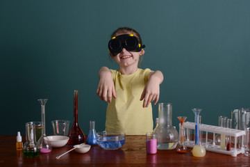 girl in safety glasses at home doing experiments with chemicals. school experiments at home.