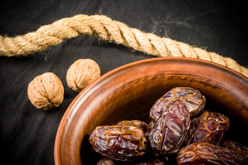 Big luxury dried date fruit in bowls on the dark surface, kurma ramadan kareem concept, close up.