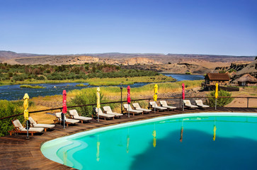 Fototapeta na wymiar View at swimming pool in Felix Unite Camp and scenic landscape at the Orange river. in Noordewer Namibia.