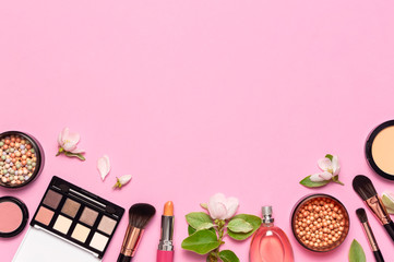 Decorative cosmetics mascara powder lipstick eyeshadow blush balls makeup brush perfume blooming spring branches on pink background top view Flat lay. Beauty blogger concept. Fashion background