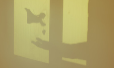 A window frame featuring an angel's silhouette and a woman's hand