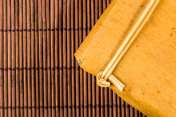 Naklejka na ściany i meble Chinese pressed PU-erh tea in bamboo leaf packaging on a bamboo Mat, close-up, macro