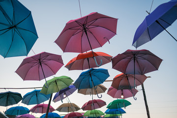 Fototapeta na wymiar Group of colorful umbrellas hanging on a rope isolated from blue sky background. colored umbrellas isolated from bright sky background.