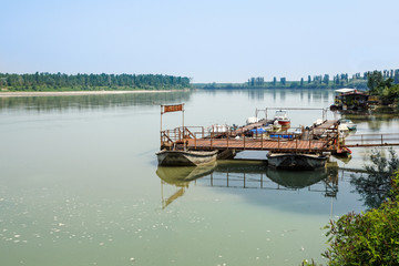 Fototapeta na wymiar Traditional fishing boats tied up on the floating dock in picturesque surrounding of the big river