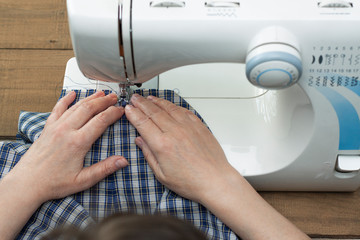 Old women's hands behind her sewing in sewing machine