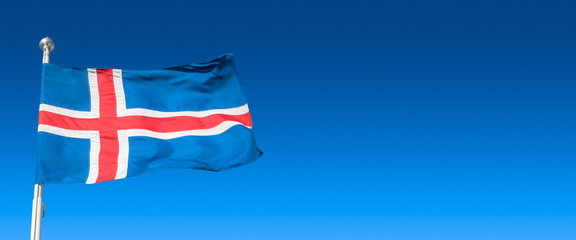 Banner with blue Icelandic national civil flag with red and white cross at blue sky background with copy space for text, closeup, details