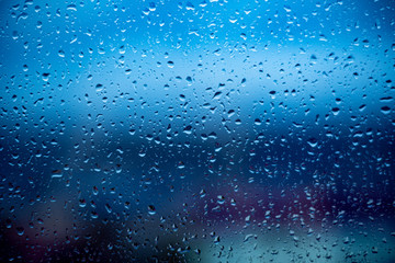 Raindrops flowing down the glass in cloudy weather in autumn and summer, a gray day, a sad day.