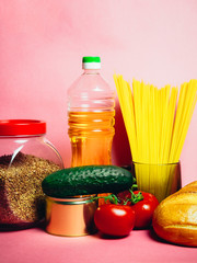 Food supplies crisis food stock for quarantine isolation period on pink. Vermicelli, pasta, canned food, bananas, butter, bread. Food Delivery, Donation, Coronavirus Quarantine.