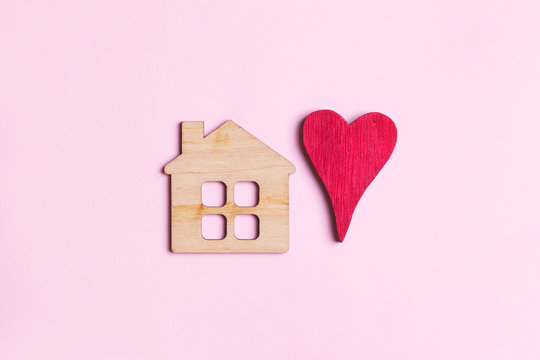 sweet home concept, mini wooden house symbol and red heart on wooden background, top view, flat lay