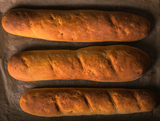 
Three loaves of bread fresh from the oven on white kitchen paper. Horizontal format. Aerial view.