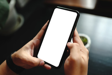 Mockup image of a woman holding and showing black mobile phone with blank screen in cafe.
