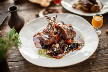 Plate with grilled ribs with sauce haute cuisine on wooden table in daylight restaurant